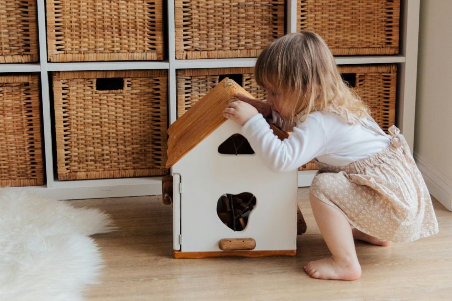 niña jugando con casita de madera