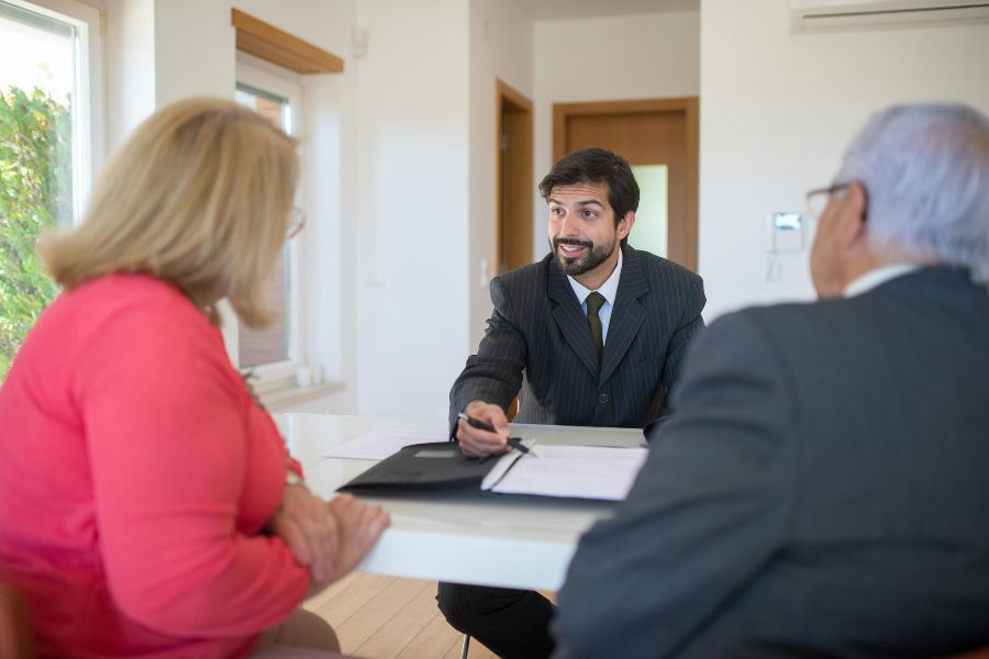 hombre trajeado explicando cosas a una pareja mayor