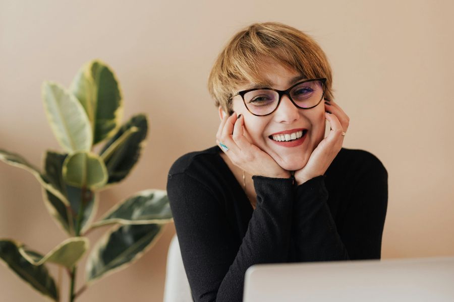 chica sonriente con gafas delante de ordenador